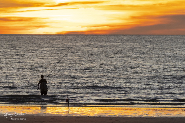 Pêcheurs sur la plage au soleil couchant